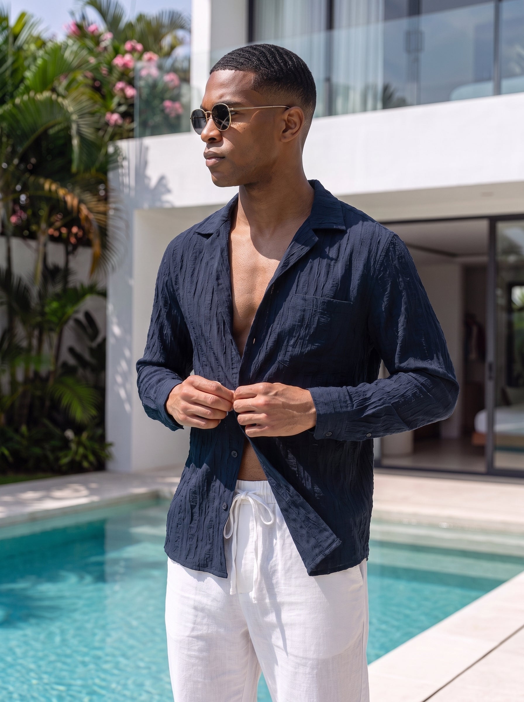 A man wearing a dark blue long sleeves shirt and off-white drawstring trousers