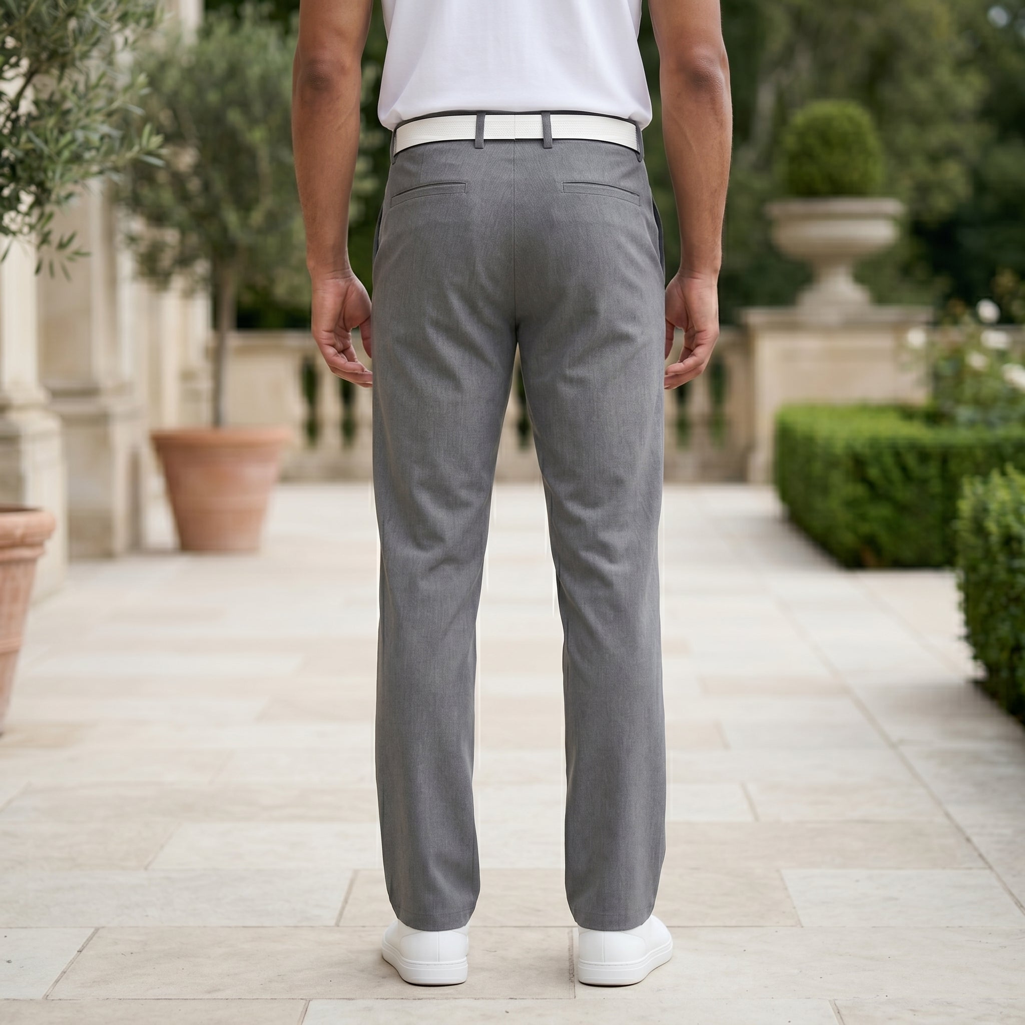 Back view of male model wearing gray tailored casual pants with a white polo shirt.