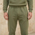 Back view of male model wearing an olive green hoodie with matching jogger pants.