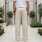 Back view of male model wearing beige textured relaxed-fit pants with a white T-shirt.