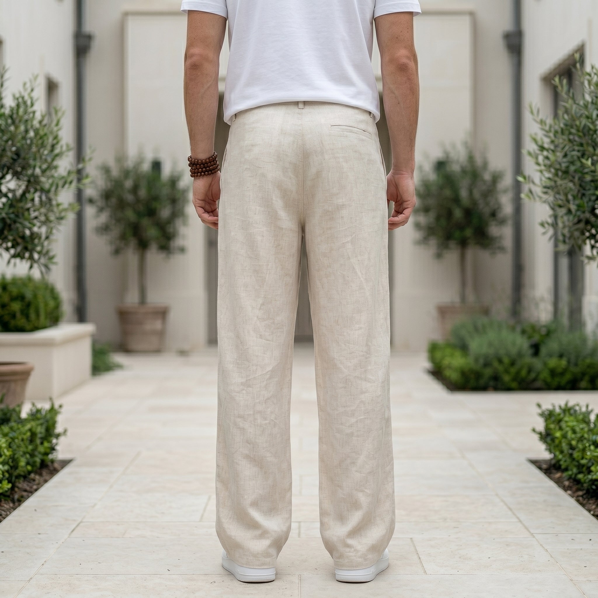 Back view of male model wearing beige textured relaxed-fit pants with a white T-shirt.