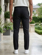 Back view of male model wearing black casual pants with a white short-sleeve polo shirt.