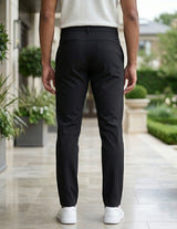 Back view of male model wearing black casual pants with a white short-sleeve polo shirt.