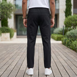 Back view of male model wearing black jogger pants with a tapered fit.