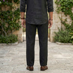 Back view of male model wearing black relaxed-fit casual pants with a black long-sleeve shirt.