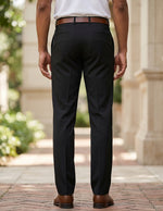 Back view of male model wearing black tailored dress pants with a white long-sleeve shirt.