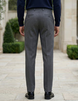 Back view of male model wearing dark gray pleated tailored pants with a navy long-sleeve top.