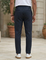 Back view of male model wearing navy pinstripe relaxed-fit pants with a white T-shirt.