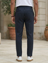Back view of male model wearing navy pinstripe relaxed-fit pants with a white T-shirt.