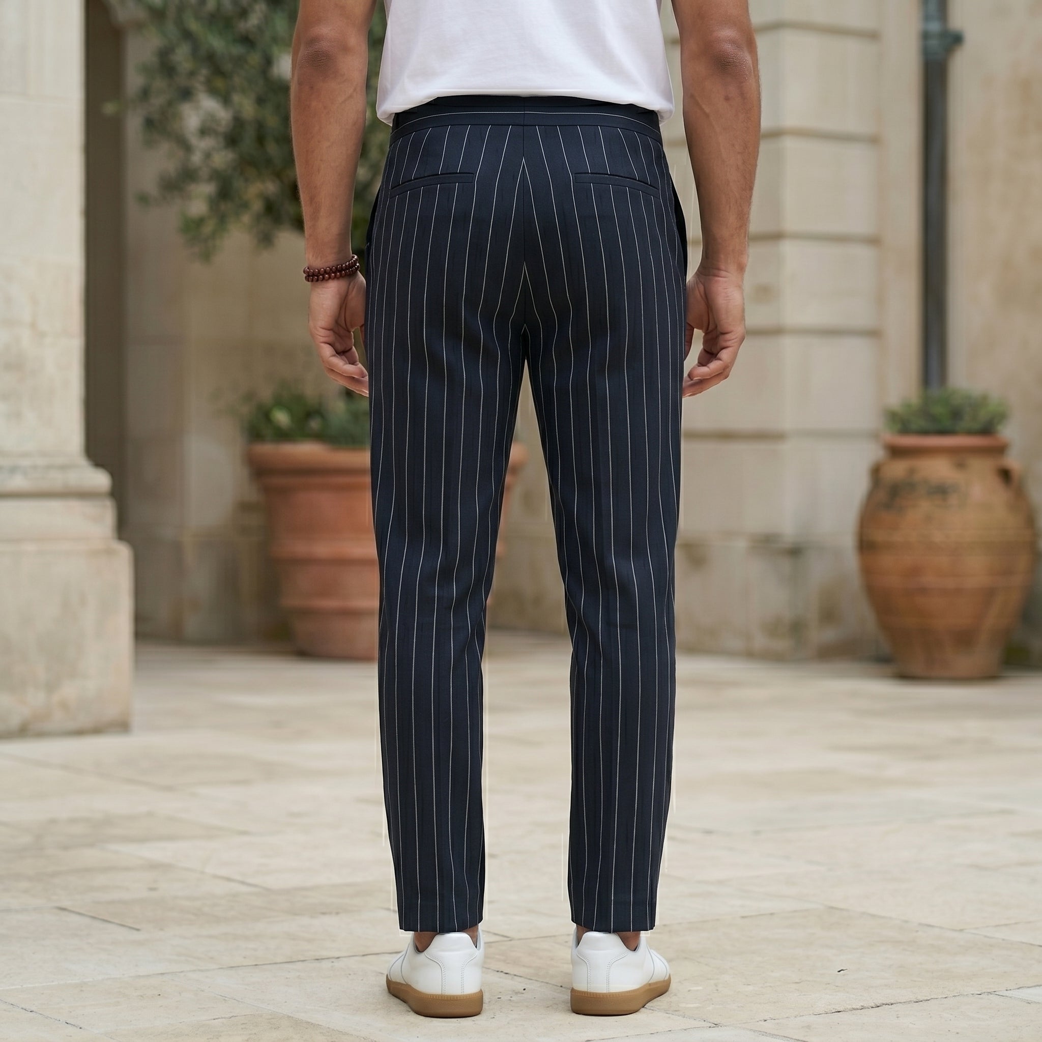 Back view of male model wearing navy pinstripe relaxed-fit pants with a white T-shirt.