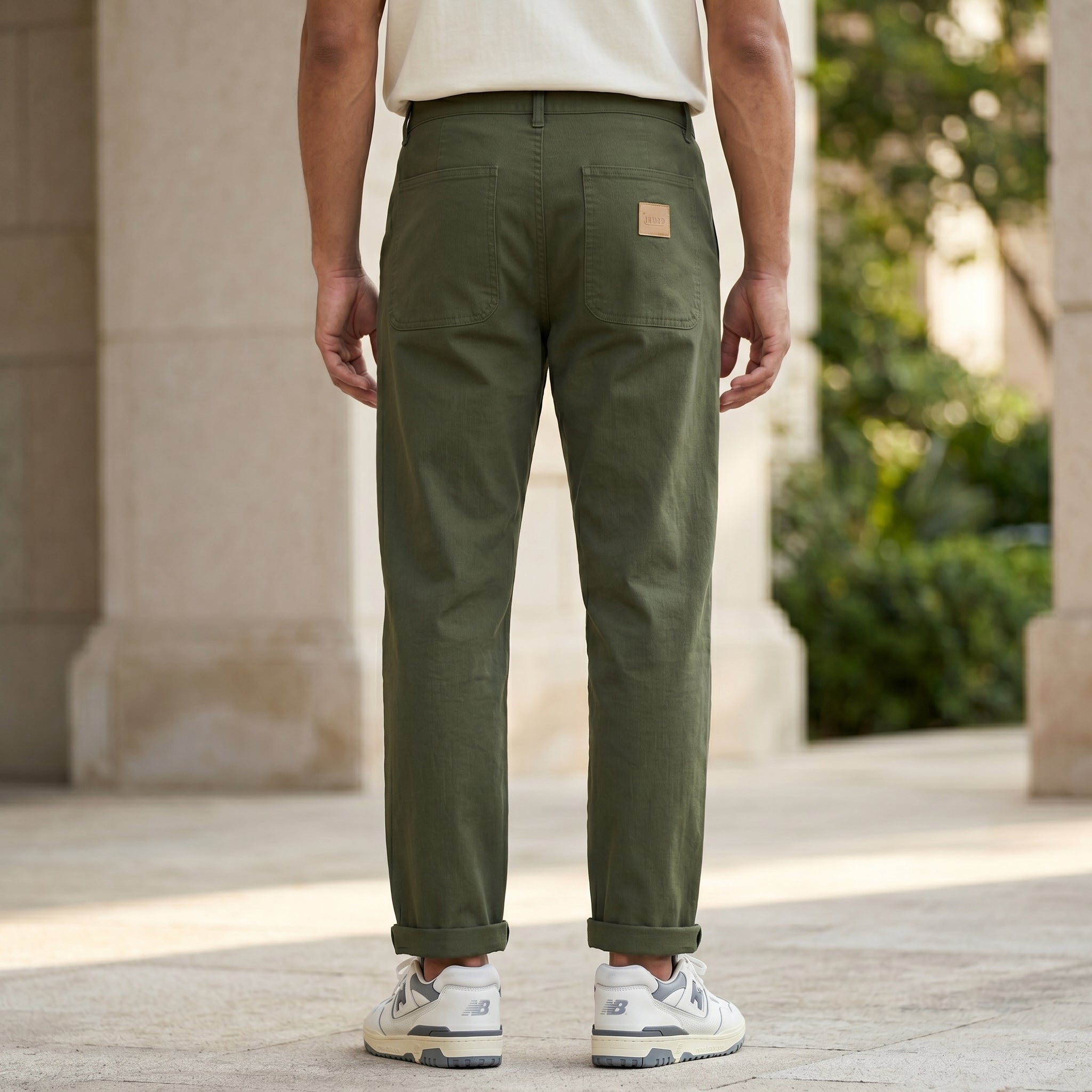 Back view of male model wearing olive green drawstring jogger pants with a beige T-shirt.