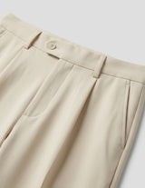 Beige pleated pants on a light gray background, bottom fabric detail