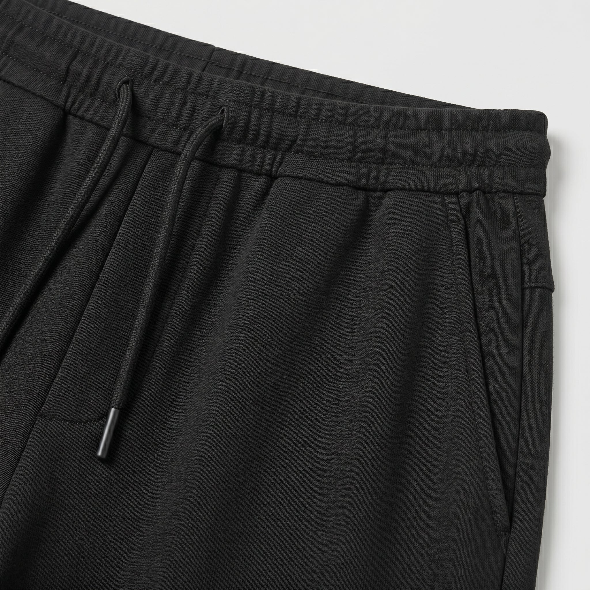 Black men’s lightweight drawstring pants with elastic waistband and clean casual fit close-up details