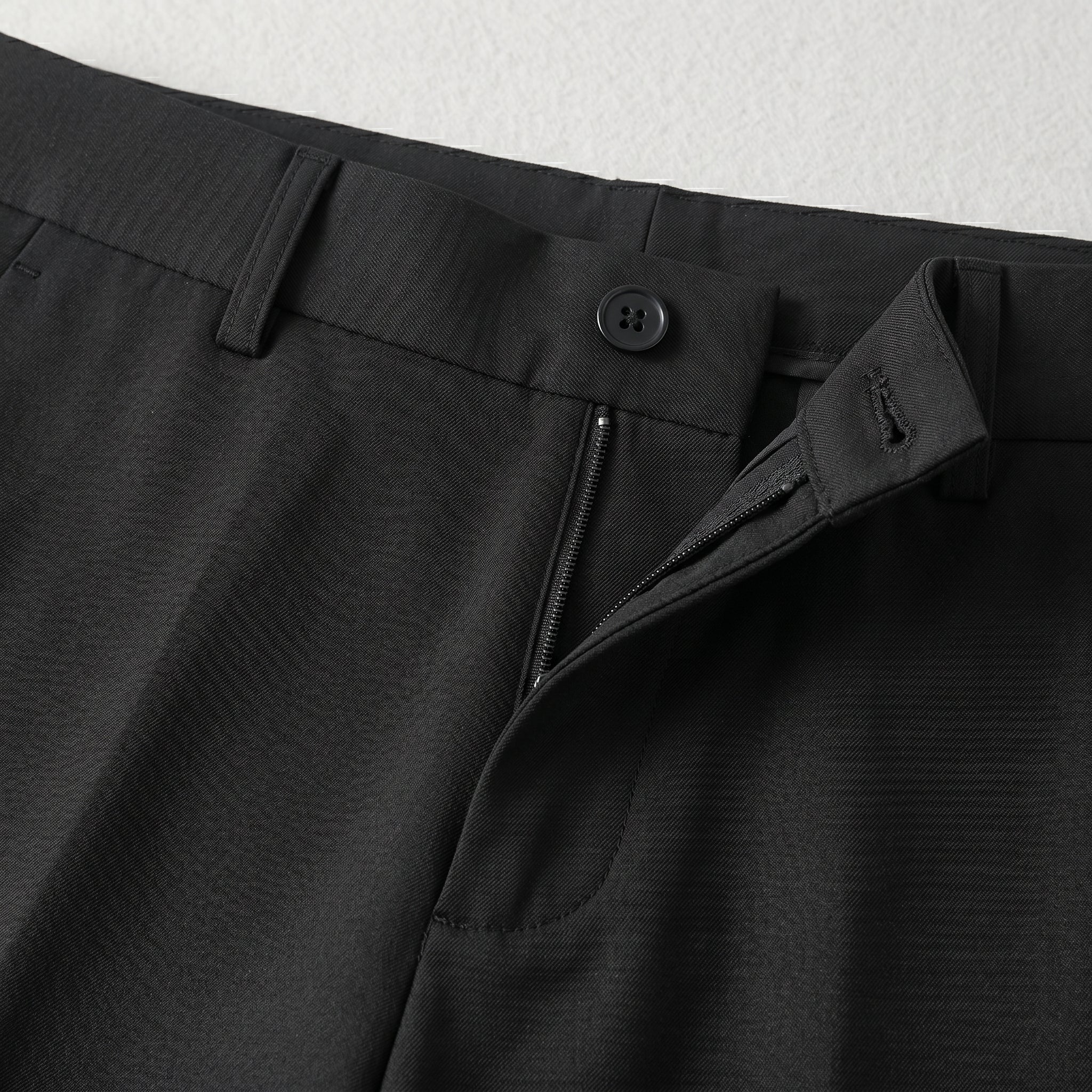 Black men’s pleated tailored pants with clean front closure and straight fit close-up details
