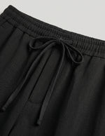 Black pants with drawstring waist on a light gray background