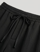 Black pants with drawstring waist on a light gray background