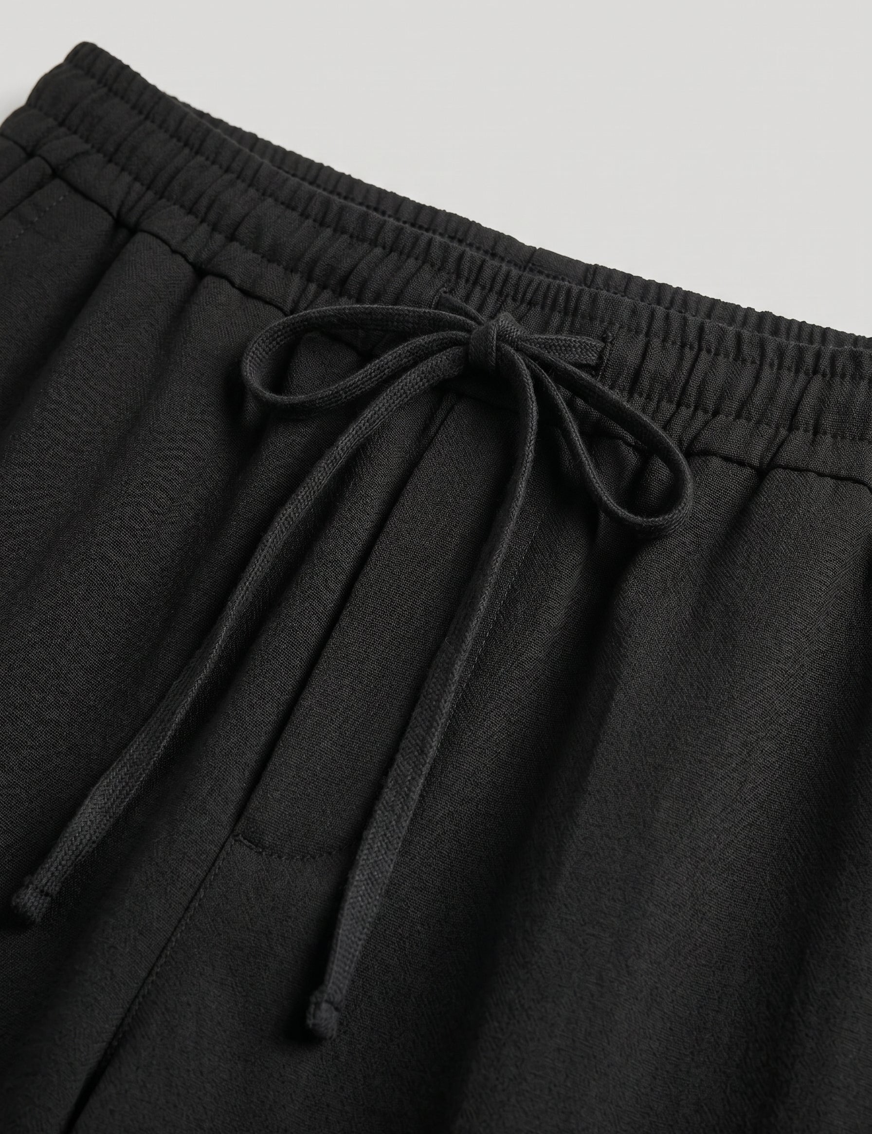 Black pants with drawstring waist on a light gray background