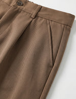 Brown men’s pleated pocketed trousers with button waistband close-up