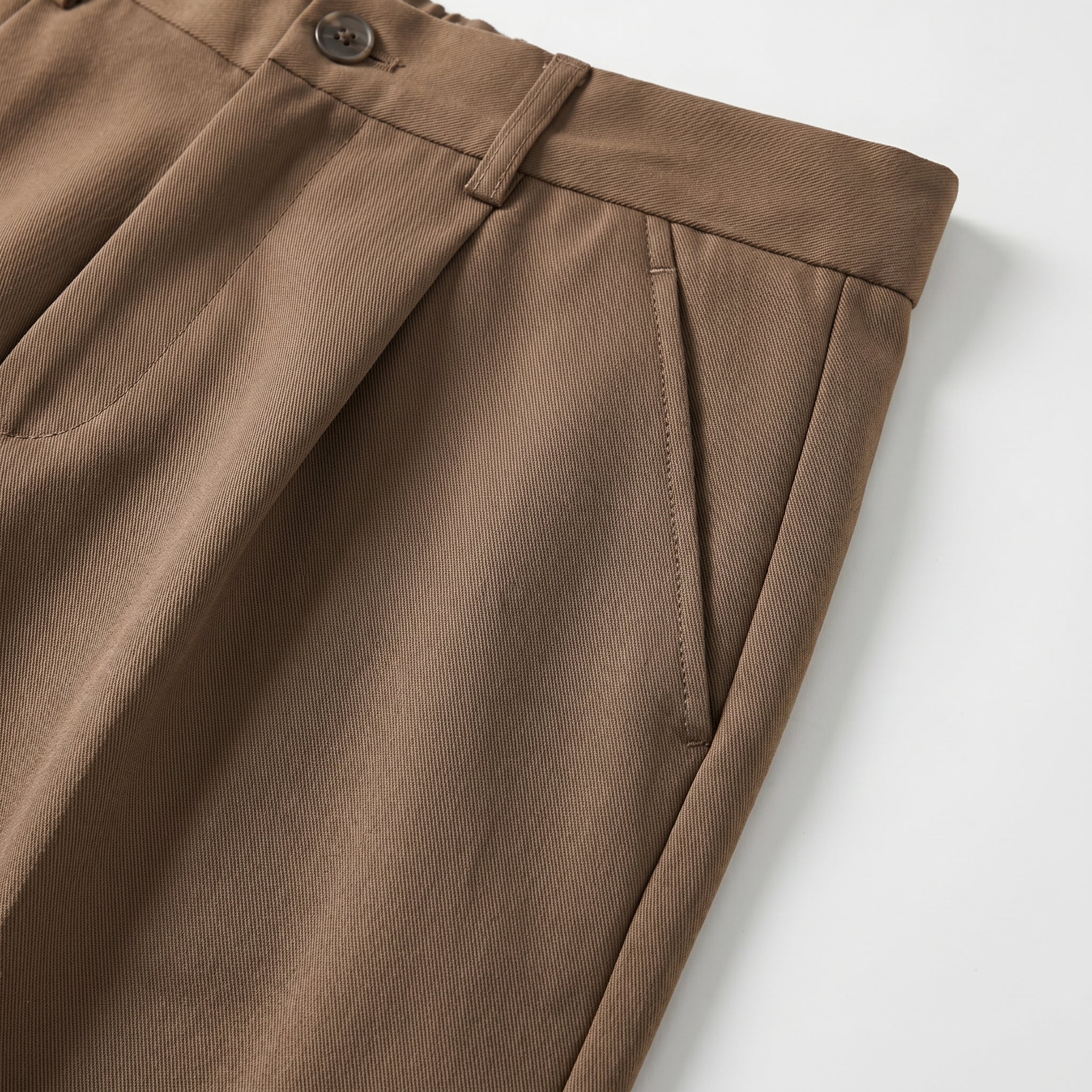Brown men’s pleated pocketed trousers with button waistband close-up