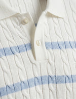 Celeste - Close-up of a white cable knit sweater with blue stripes and buttons.