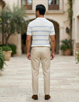 Celeste - Man walking away in a courtyard wearing a striped shirt and beige pants.
