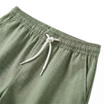 Close-up detail of sage green drawstring shorts with elastic waistband and beige rope tie.