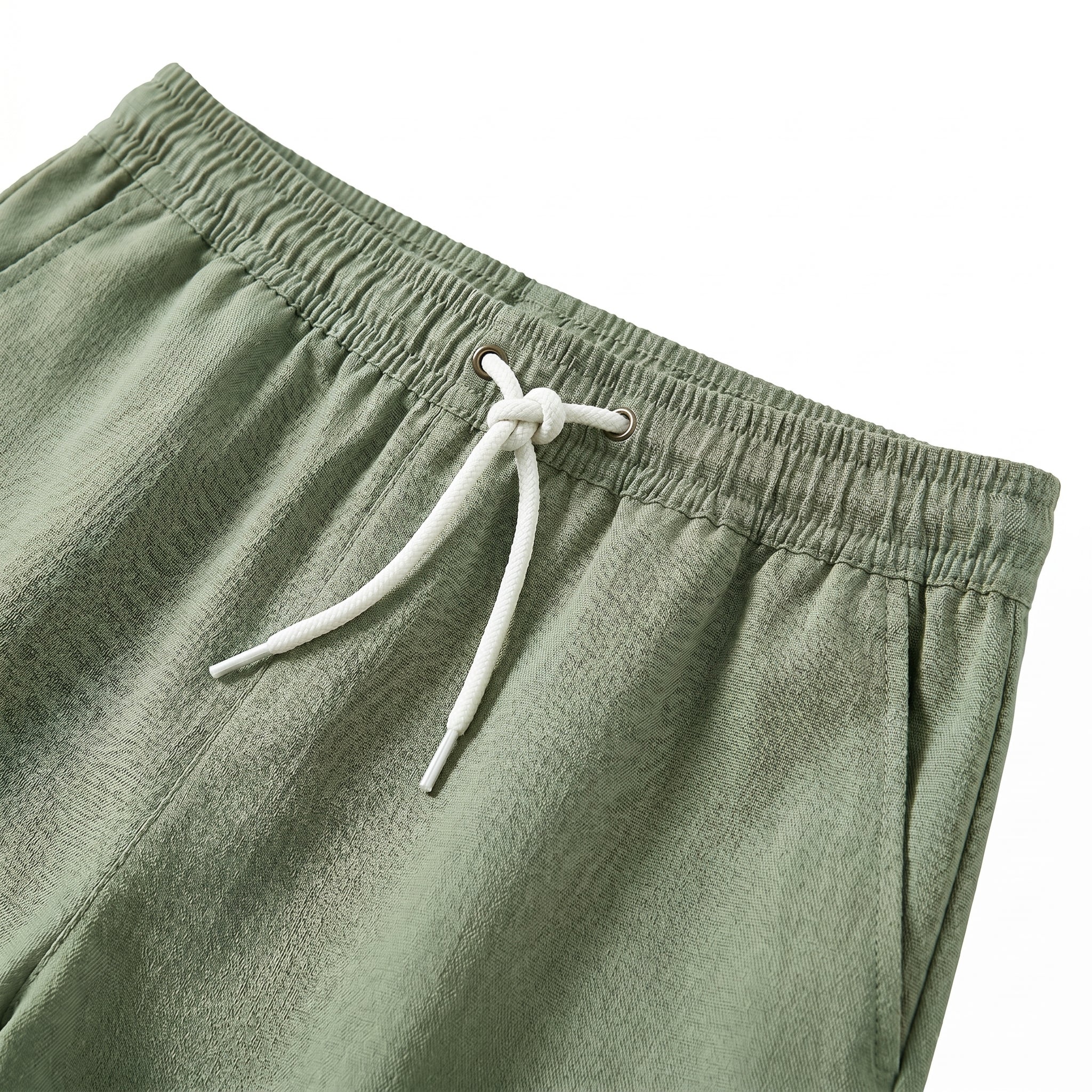 Close-up detail of sage green drawstring shorts with elastic waistband and beige rope tie.