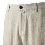 Close-up detail of beige textured pants waistband with button closure and soft fabric.