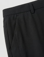 Close-up detail of black casual pants waistband, side pocket, and smooth fabric.