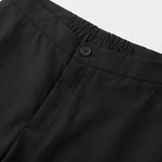 Close-up detail of black casual pants waistband with button closure and smooth fabric.