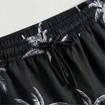 Close-up detail of black palm print drawstring shorts with elastic waistband and black tie.
