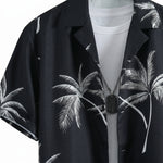 Close-up detail of black palm print short-sleeve button-up shirt fabric and collar.
