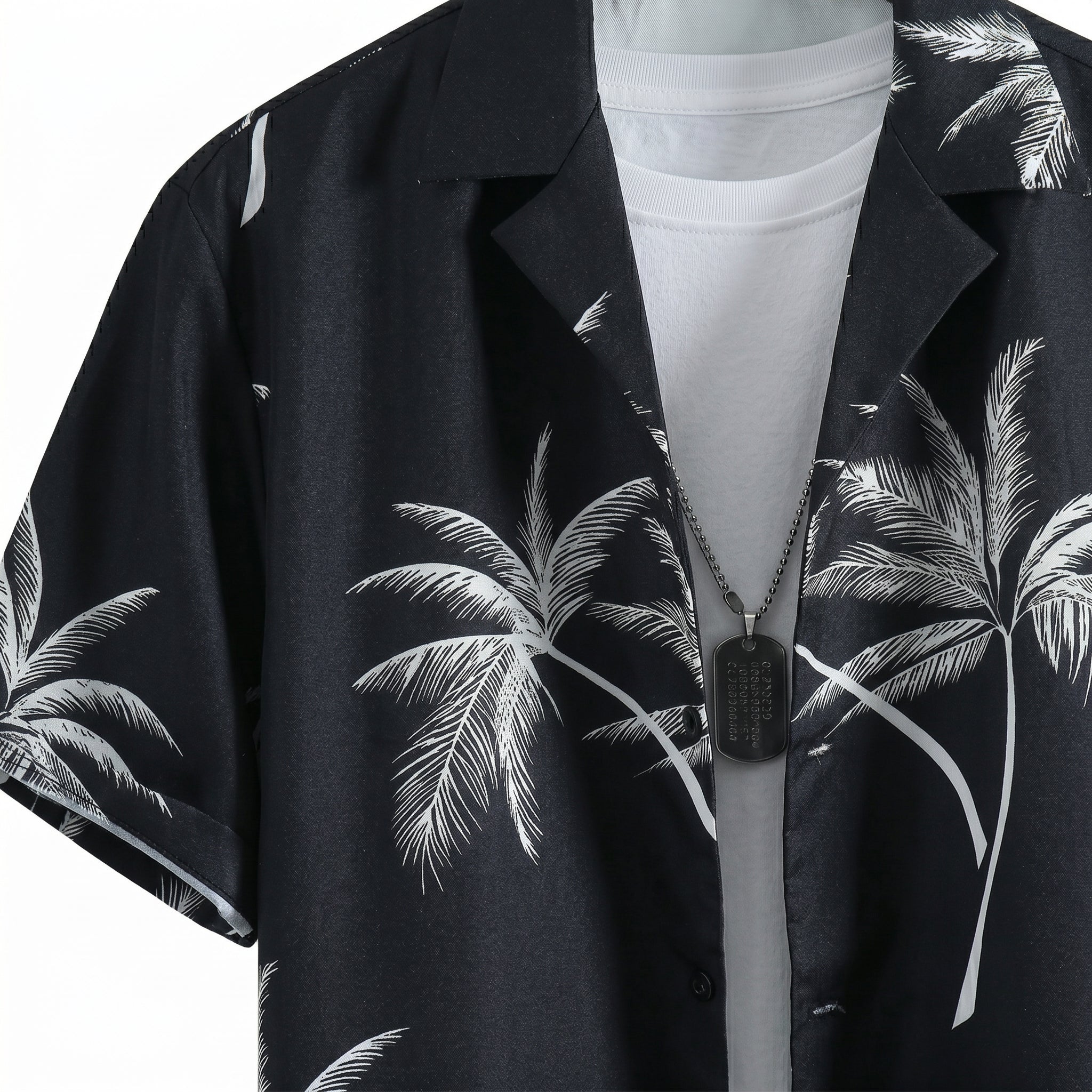 Close-up detail of black palm print short-sleeve button-up shirt fabric and collar.