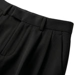 Close-up detail of black pleated pants waistband with button closure and soft fabric.