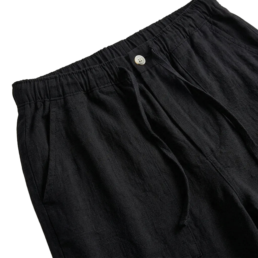 Close-up detail of black relaxed-fit pants waistband with button closure and soft fabric.