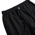 Close-up detail of black relaxed-fit pants waistband with button closure and soft fabric.