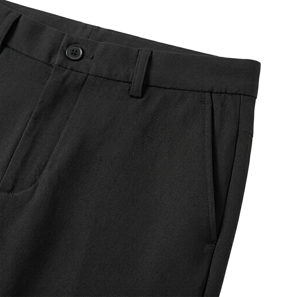 Close-up detail of black tailored pants waistband with belt loops, button closure, and smooth fabric.