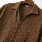 Close-up detail of brown textured short-sleeve shirt fabric and collar.