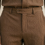 Close-up detail of brown textured pants waistband and front closure.