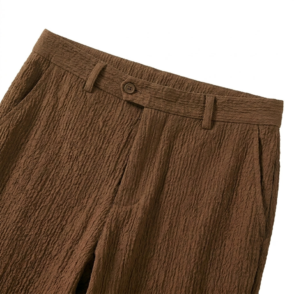 Close-up detail of brown textured straight-leg pants with belt loops and button closure.
