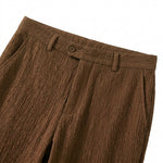 Close-up detail of brown textured straight-leg pants with belt loops and button closure.