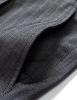 Close-up detail of dark gray pleated pants waistband with belt loops, button closure, and smooth fabric.
