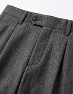 Close-up detail of dark gray tailored pants fabric, pocket, and clean seam finish.