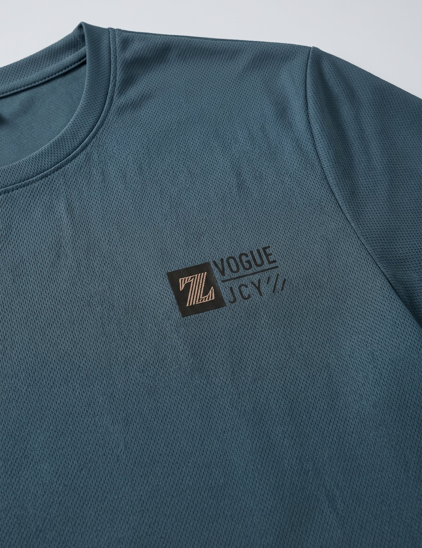 Close-up detail of dark teal blue T-shirt fabric with crew neckline and subtle chest logo.