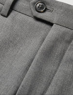 Close-up detail of gray pleated pants waistband with belt loops, button closure, and smooth fabric.