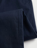 Close-up detail of navy tailored pants waistband with belt loops, button closure, and smooth fabric.