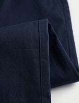 Close-up detail of navy tailored pants waistband with belt loops, button closure, and smooth fabric.