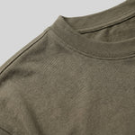 Close-up detail of olive green T-shirt fabric with crew neckline and subtle chest logo.