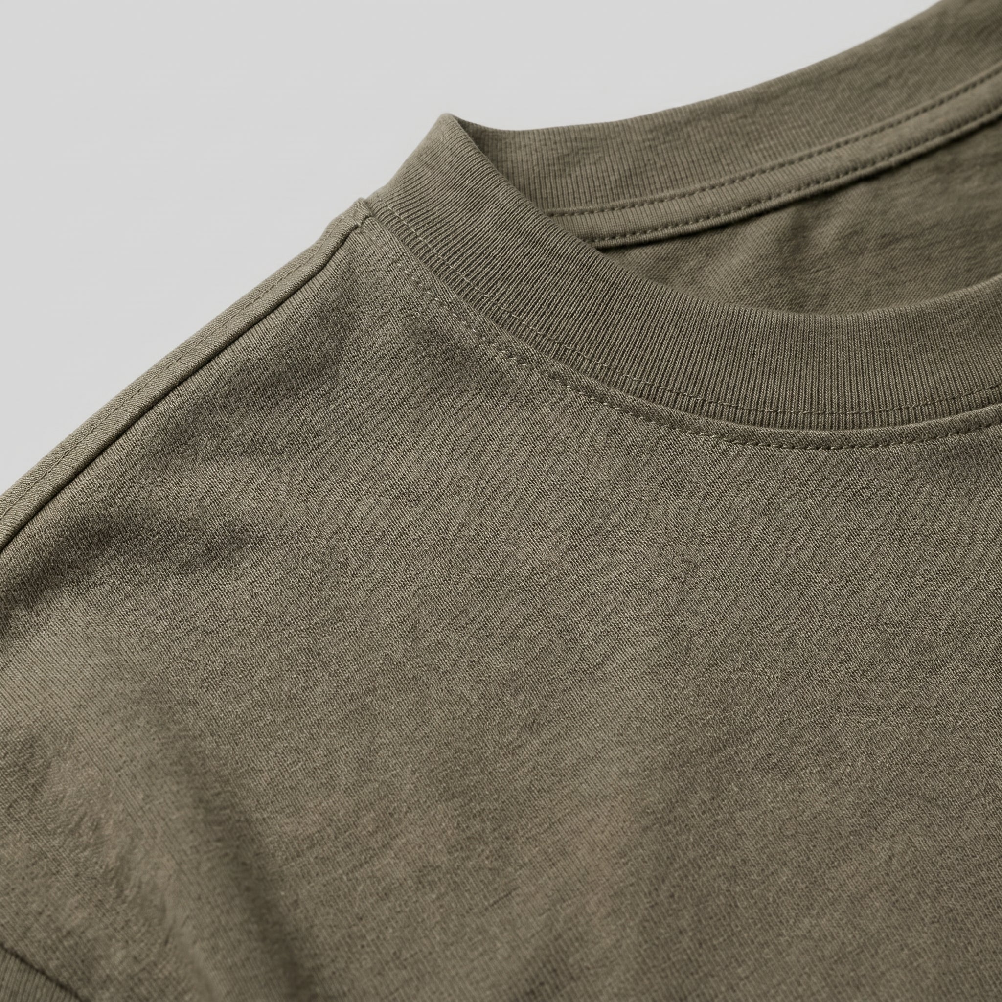 Close-up detail of olive green T-shirt fabric with crew neckline and subtle chest logo.