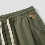 Close-up detail of olive green jogger pants with elastic waistband, drawstring, and side pocket.